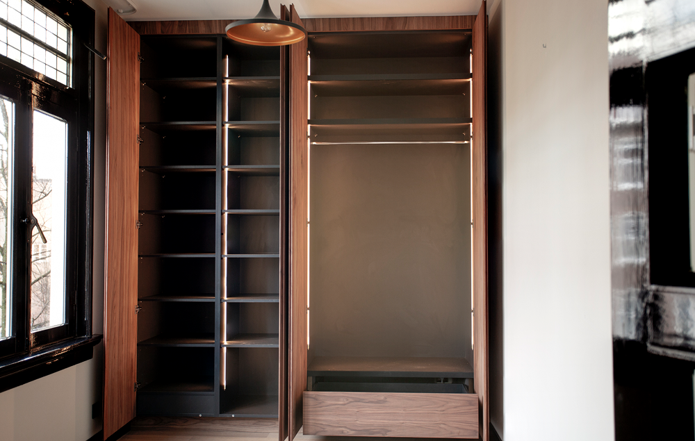 Binnenzijde van de notenhouten kastenwand met legplanken en laden